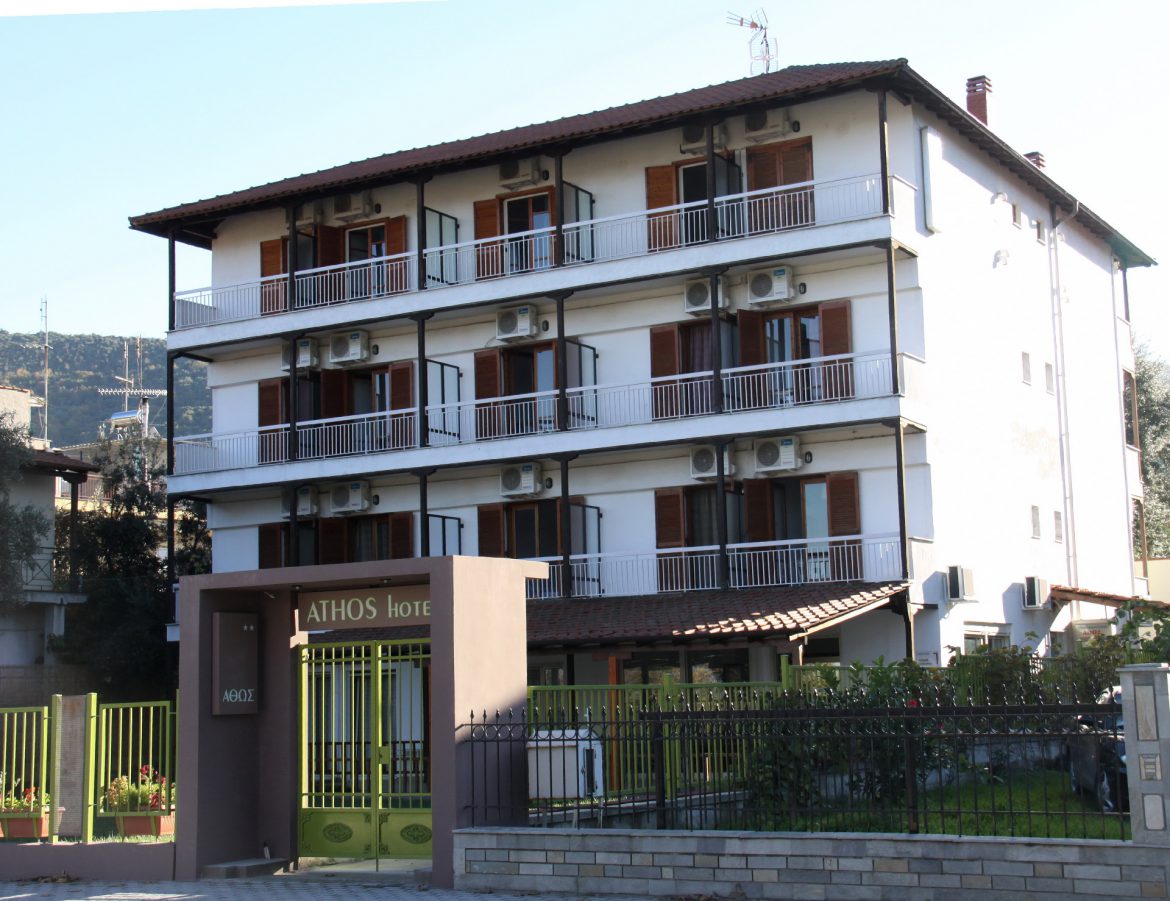 The four-storey Athos Hotel seen from the street, balconies shaded by the mountain behind Stavros