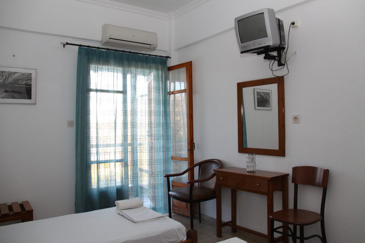 A room interior with television, mirror, writing desk and chairs
