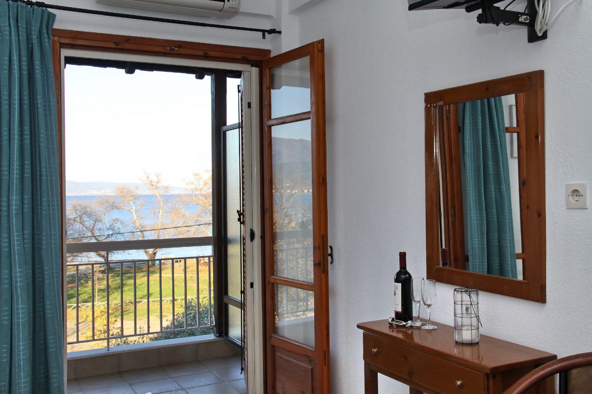 A sea-view room, balcony doors open over the trees towards the water